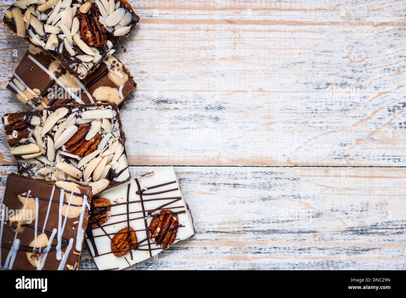 Assorted chocolate caramel bark pieces arranged on wooden background from above with copy space Stock Photo
