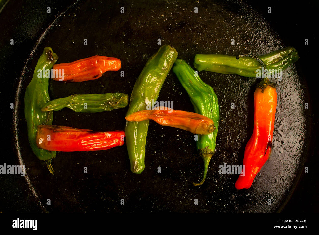 green and orange roasted peppers in cast iron skillet overhead Stock