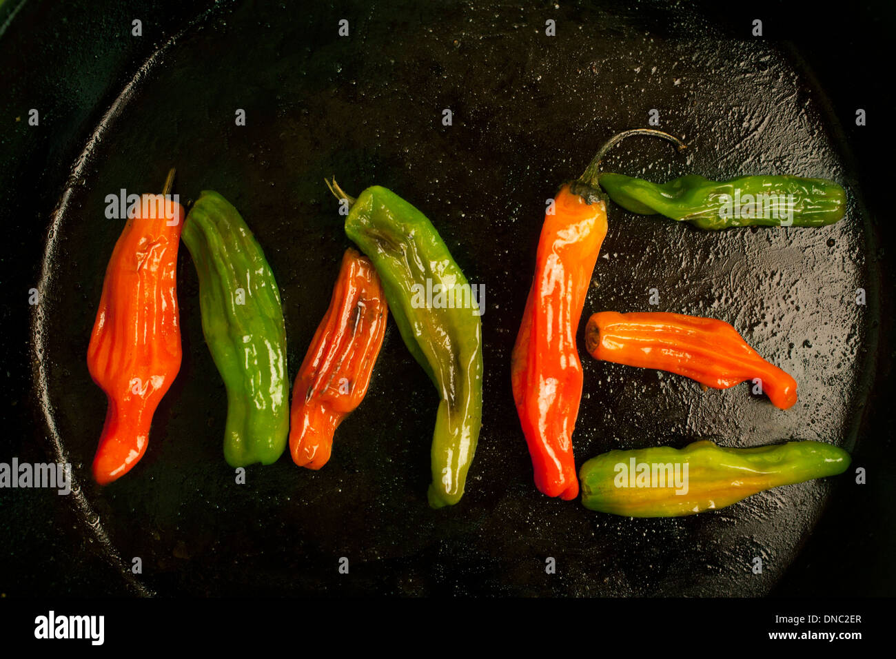 green and orange roasted peppers in cast iron skillet overhead Stock