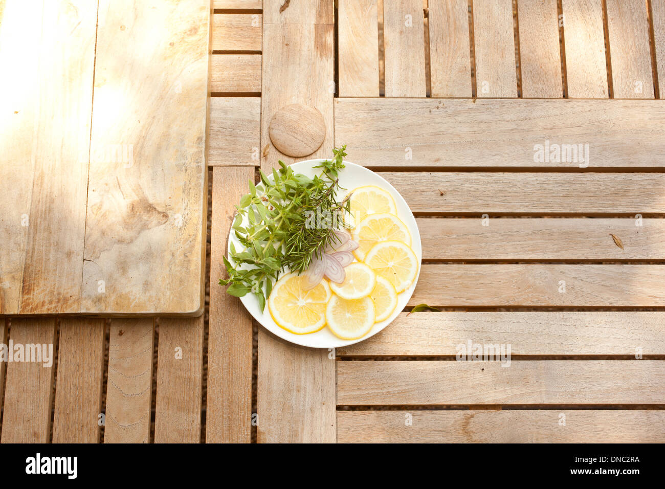 Lemon slices with fresh herbs on white plate overhead Stock Photo