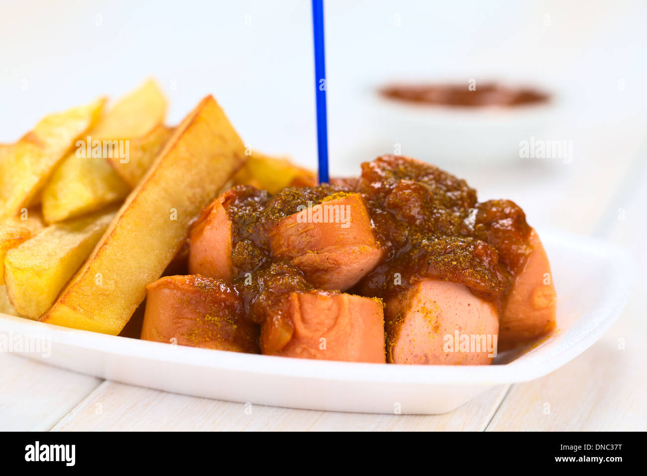 German fast food called Currywurst served with French fries on a disposable plate with plastic party fork Stock Photo