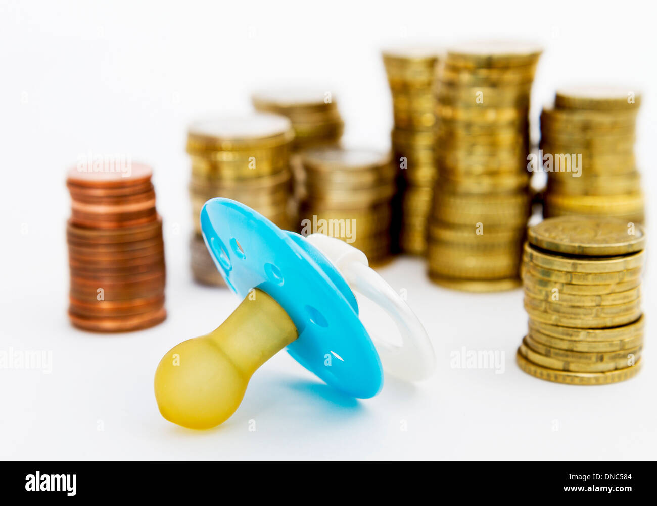 pacifier with hard money in light background. Stock Photo