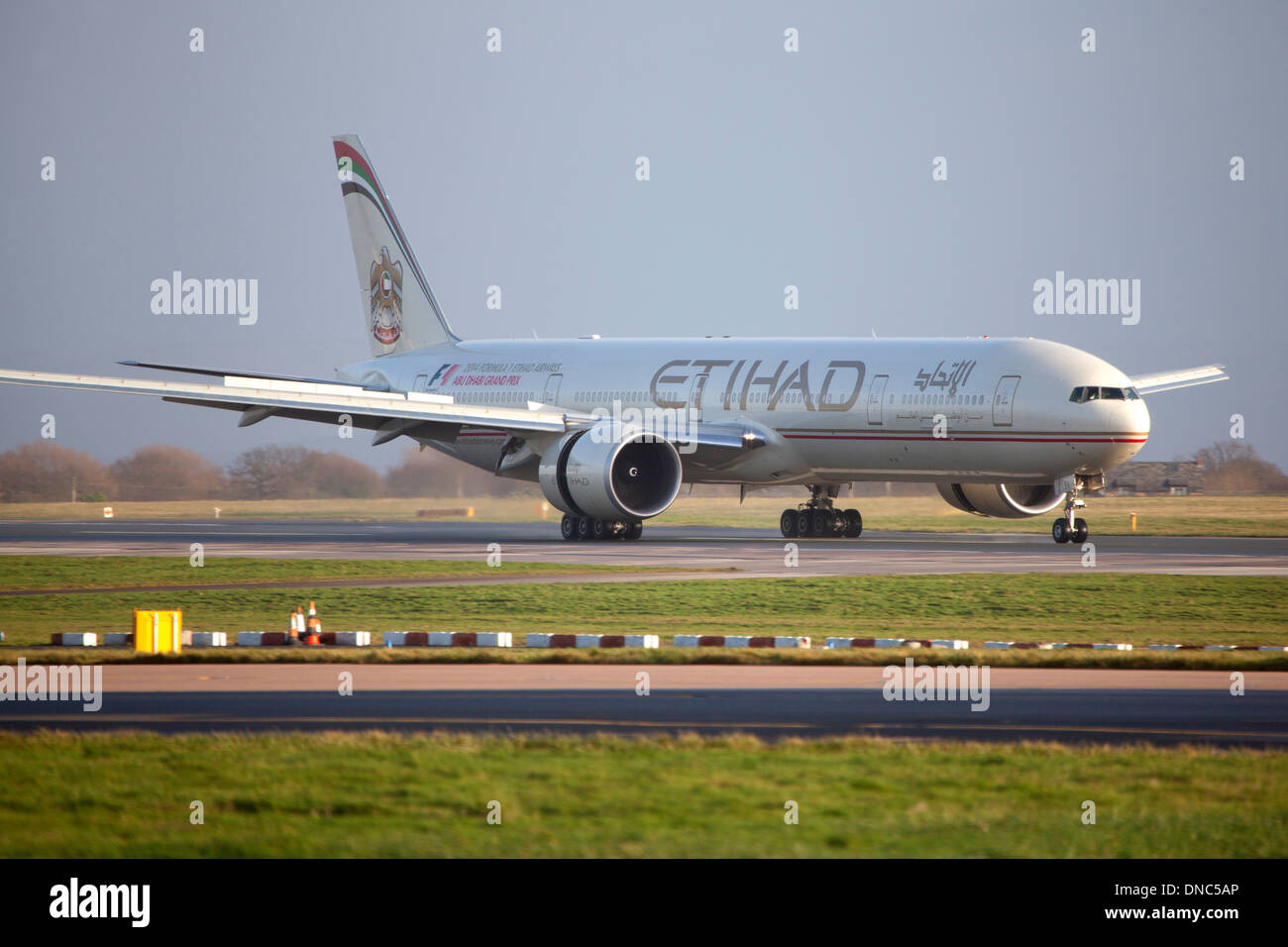 Etihad Boeing 777 aircraft landing and taxiing at Manchester Airport Stock Photo
