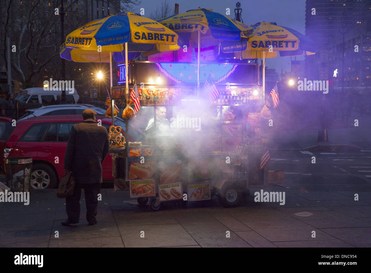 Hot dog vendor smokes up the area grilling hot dogs near City Hall Park at dusk in Manhattan, NYC. Stock Photo