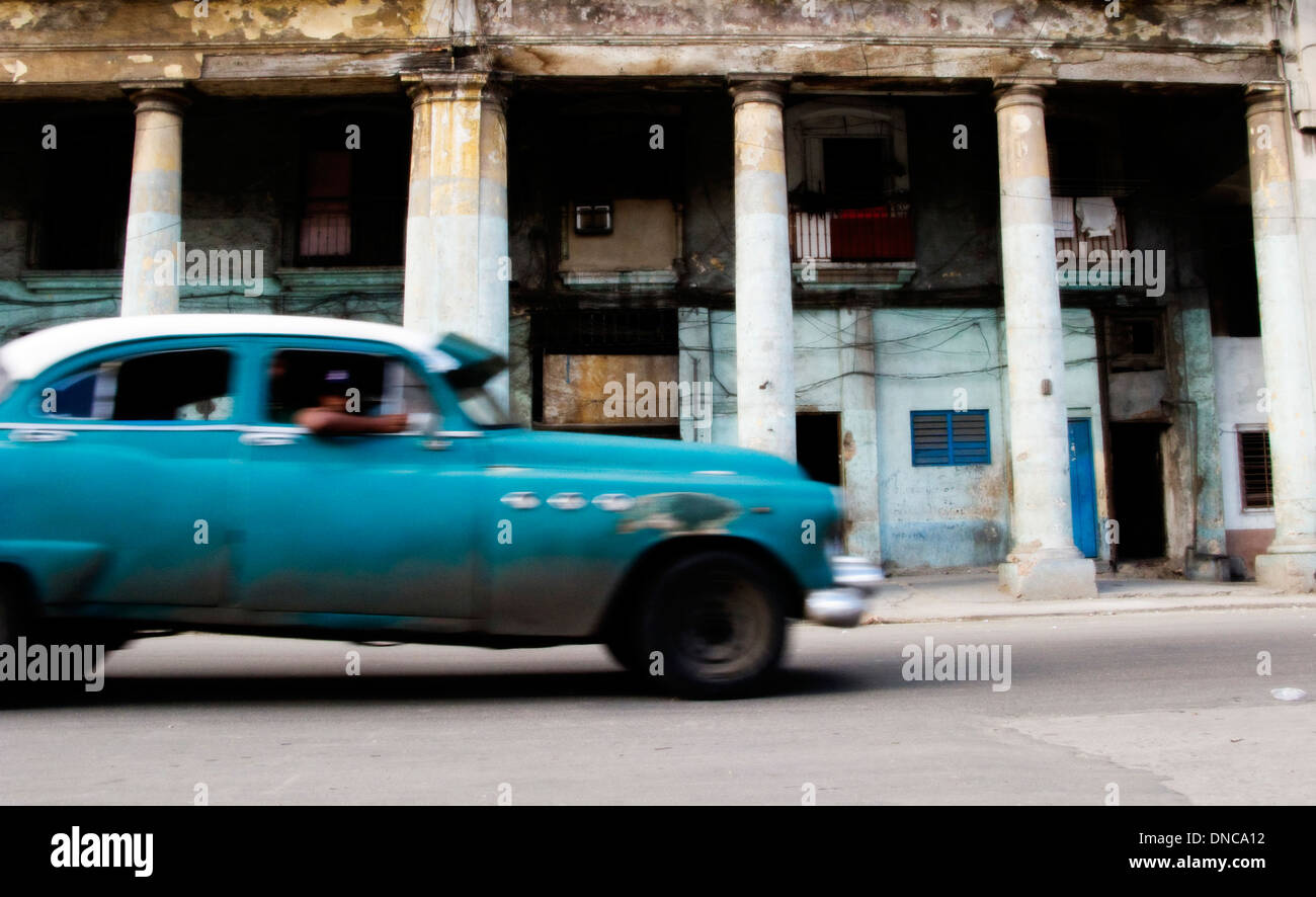 Blue old classic Cuban car moving through a street scene in Cuba's capital, Havana Stock Photo