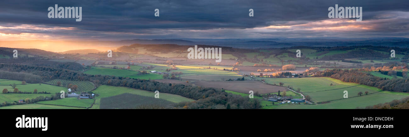 The last rays of light dart across the Herefordshire countryside seconds before the Winter sun is obscured by heavy clouds. Stock Photo