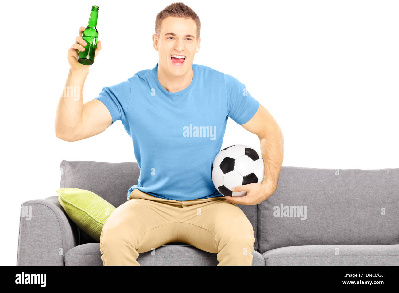 Happy cheerful male sport fan with soccer ball and beer bottle watching sport Stock Photo