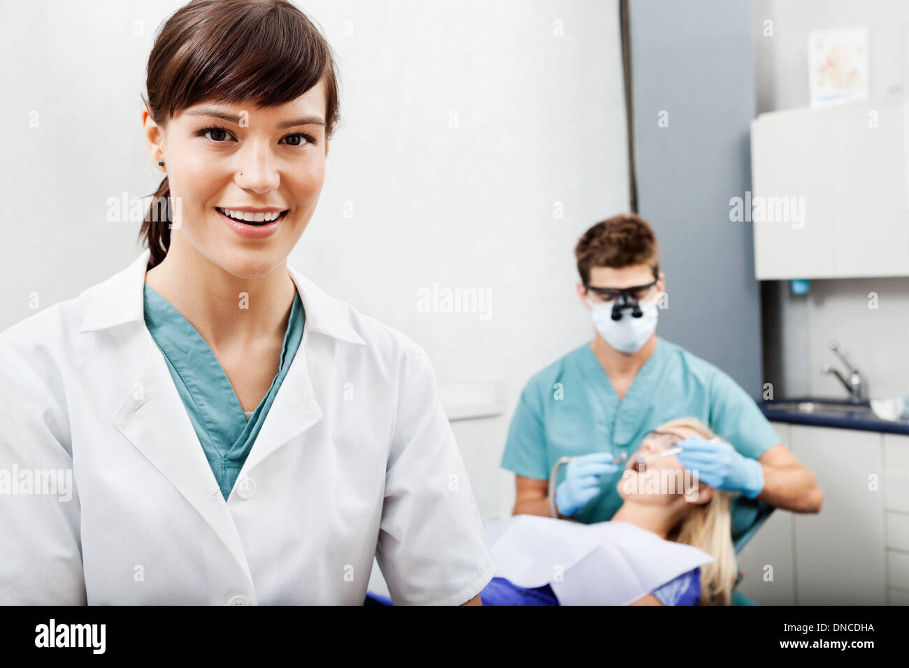 Female Assistant With Dentist Working In The Background Stock Photo