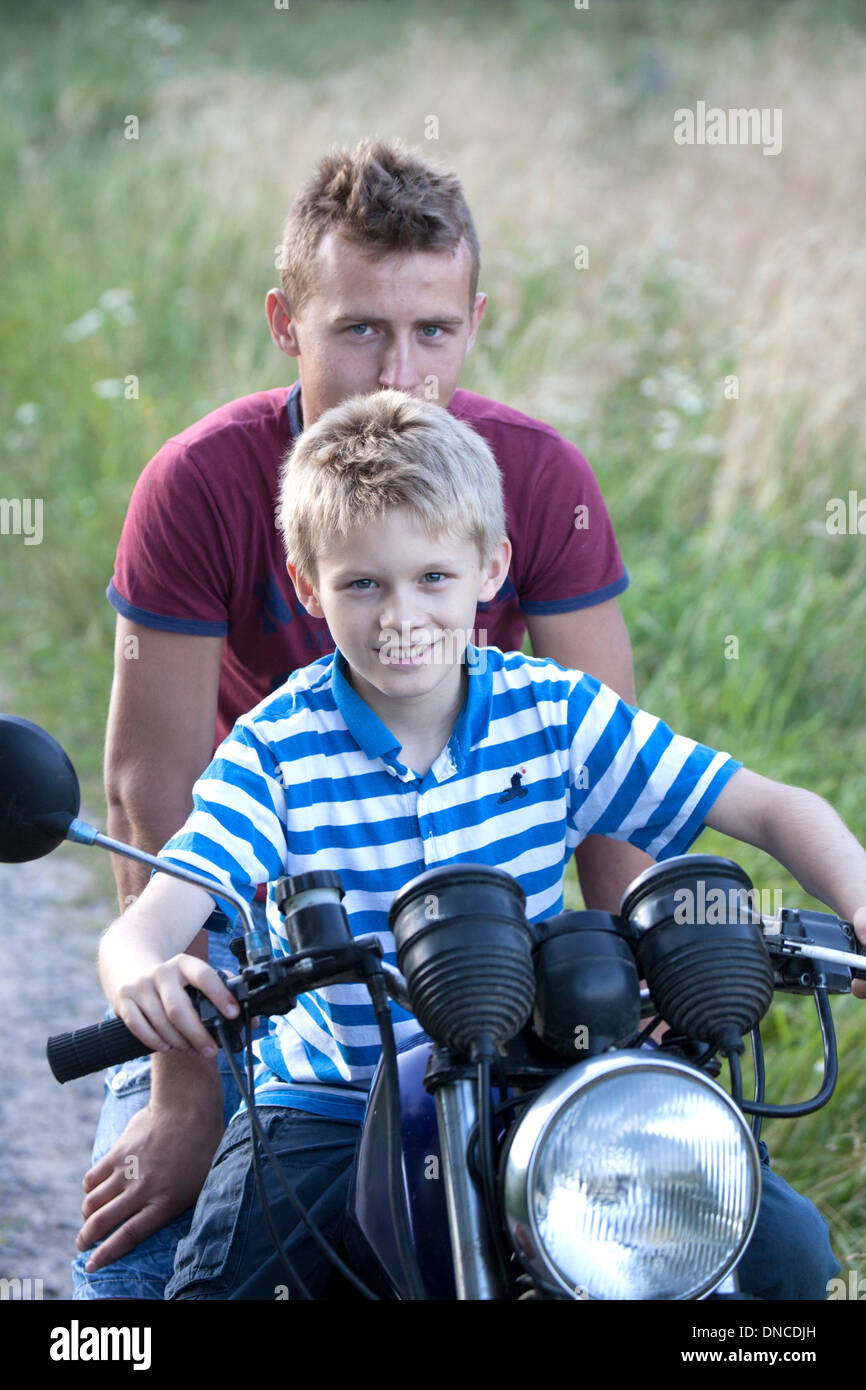 Polish teen giving ride to young happy neighbor boy on his motorcycle age 18 and 10. Zawady Central Poland Stock Photo