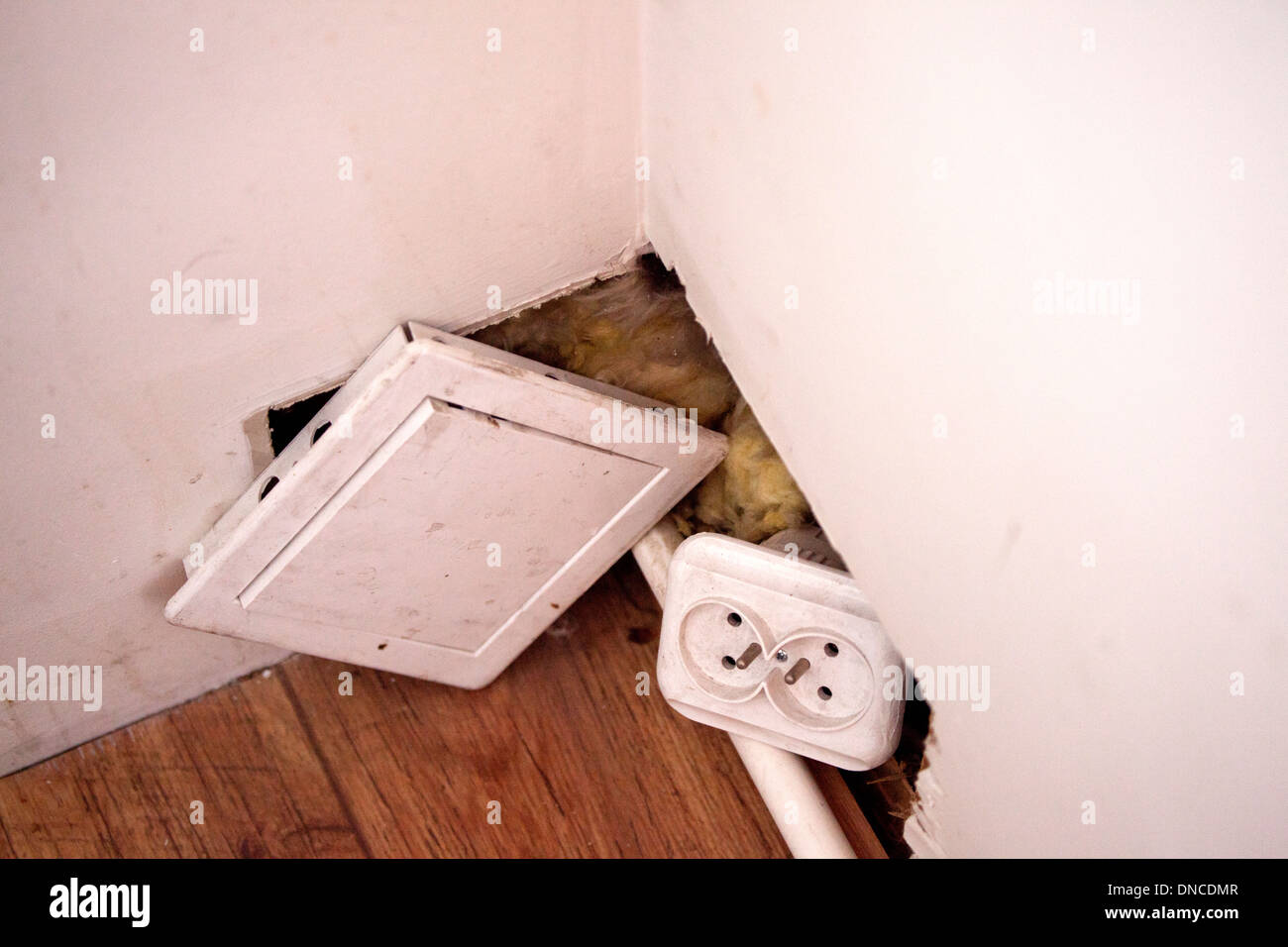 Polish electric socket needing repair hanging out of hole in wall. Lodz Central Poland Stock Photo