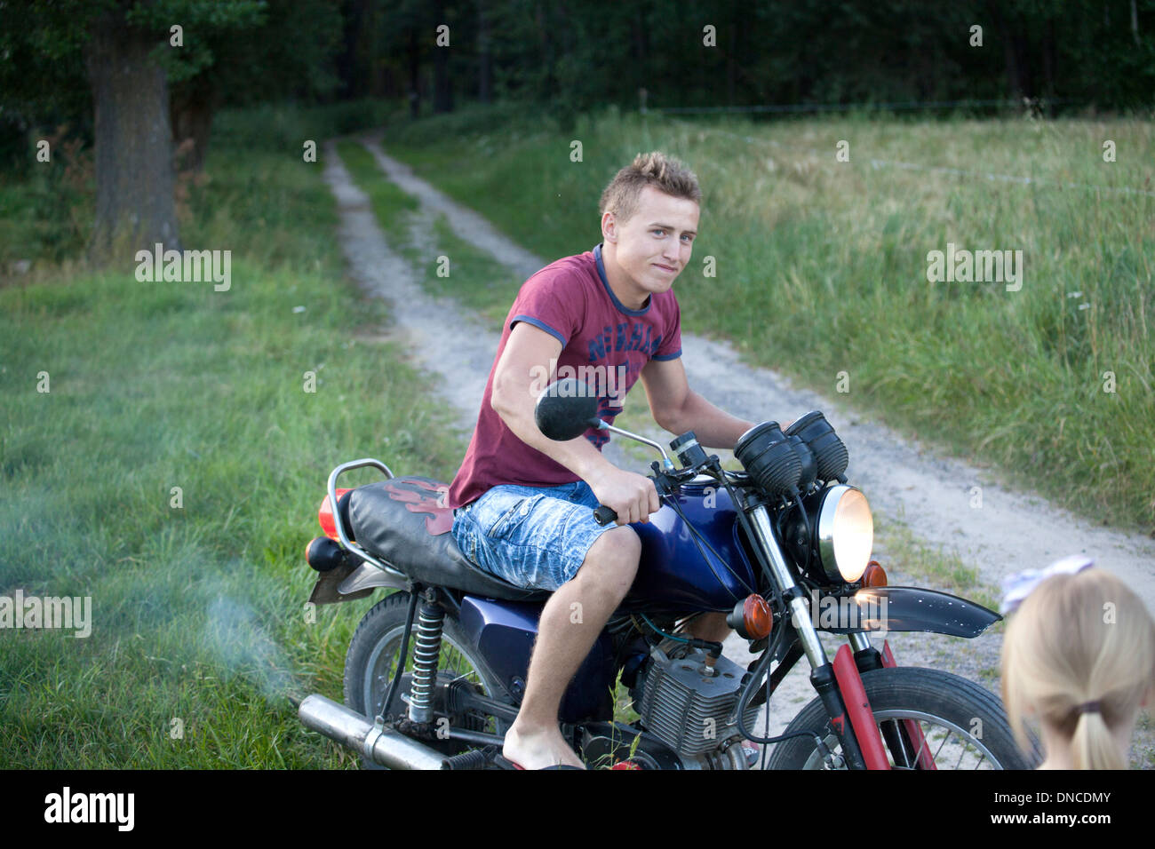 Polish teen age 18 riding his motorcycle on country dirt road. Zawady Central Poland Stock Photo