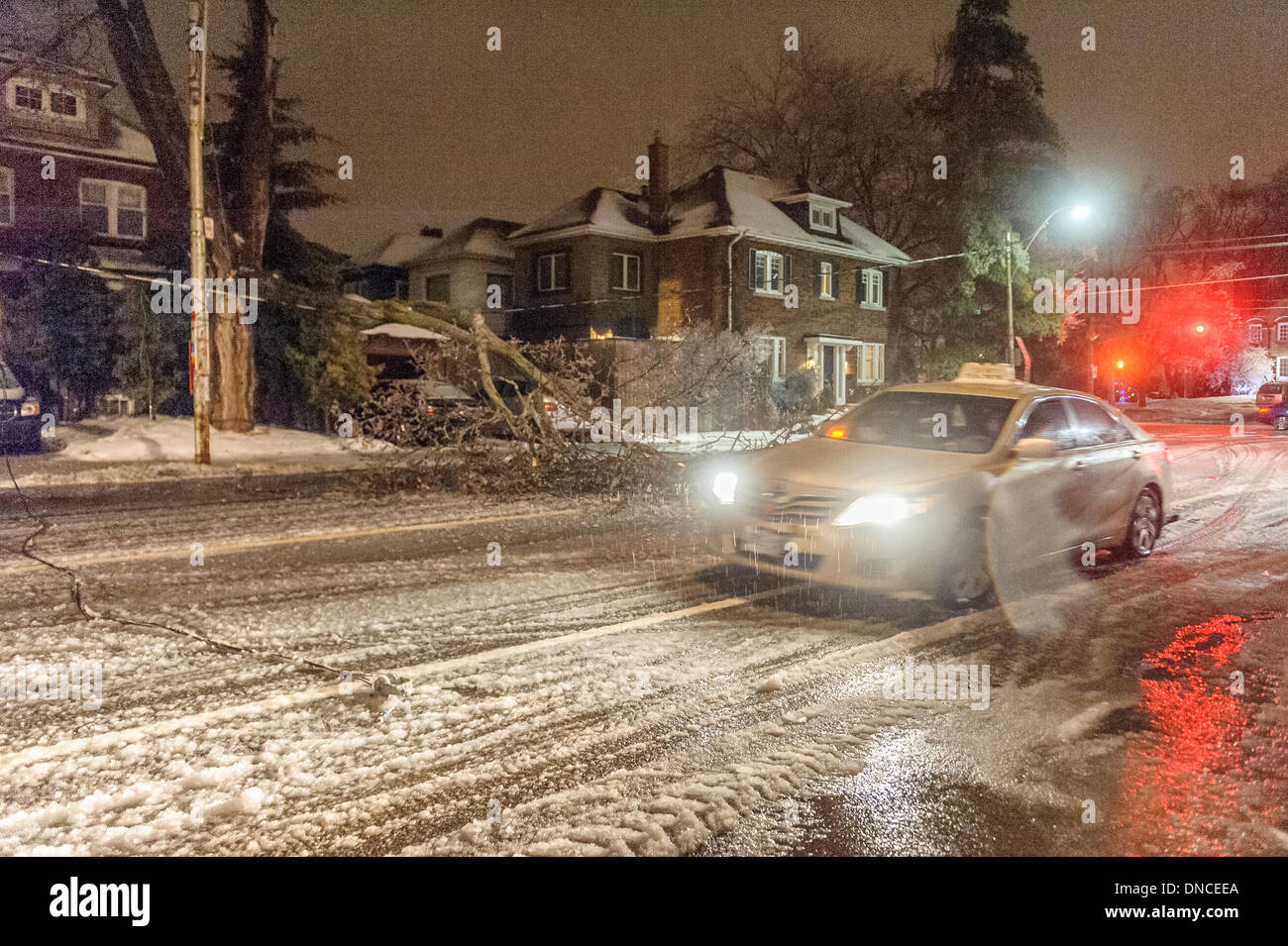 Toronto, Canada. 22nd Dec, 2013. A taxi navigates around fallen trees and power lines on Mt. Pleasant Rd. Freezing rain clung to every surface across the Greater Toronto Area, felling trees and power lines. Credit:  Victor Biro/Alamy Live News Stock Photo