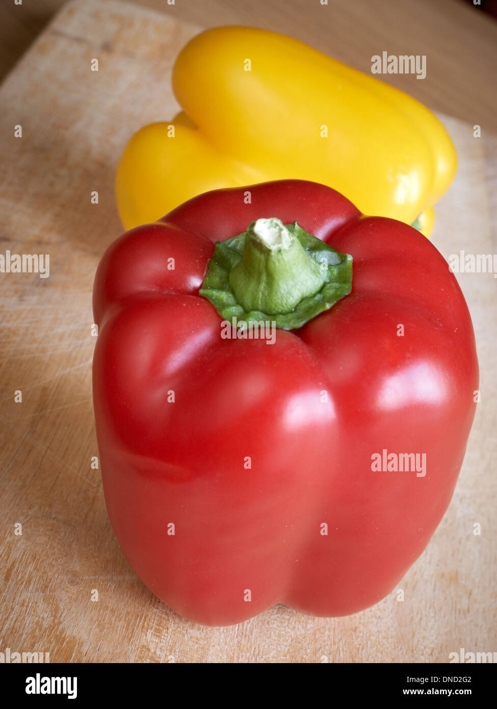 Red and yellow peppers on chopping board Stock Photo - Alamy