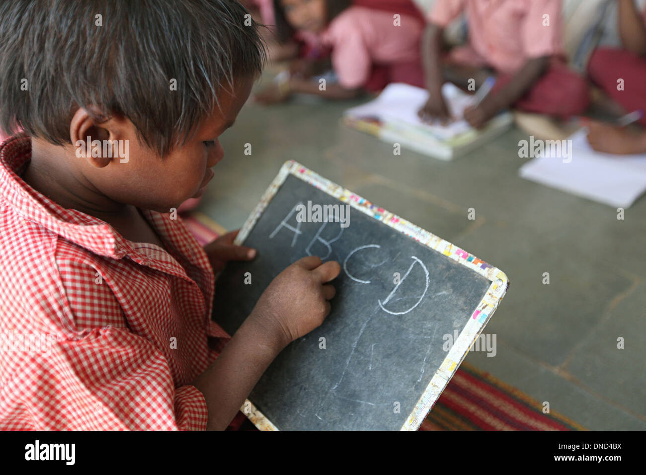 A boy studying at Ashram school writing on a slate with chalk, Rangapura, Zabua district, Madhya Pradesh Stock Photo