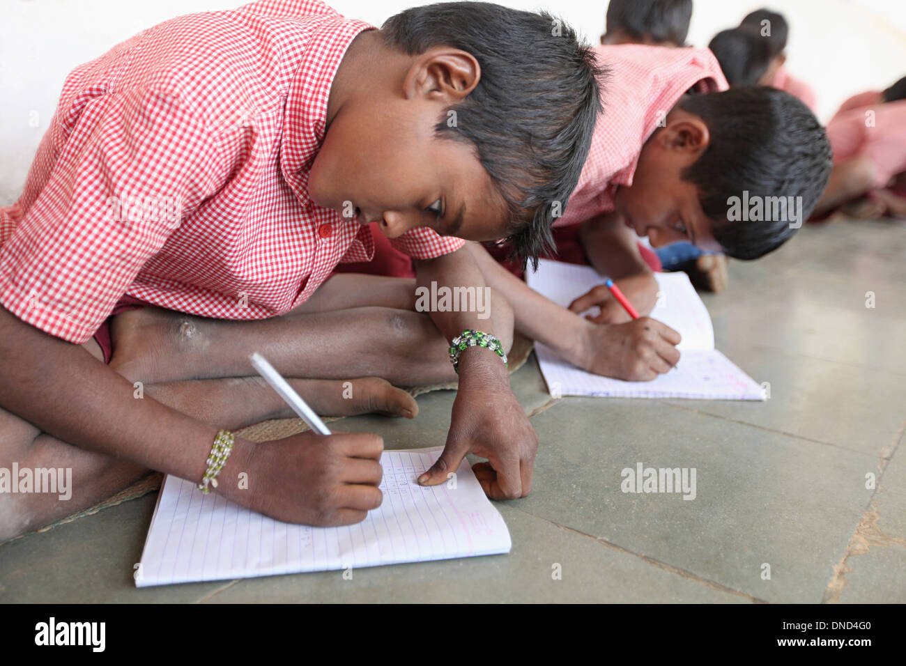Students studying at Ashram school writing in book, Rangapura, Zabua district, Madhya Pradesh Stock Photo