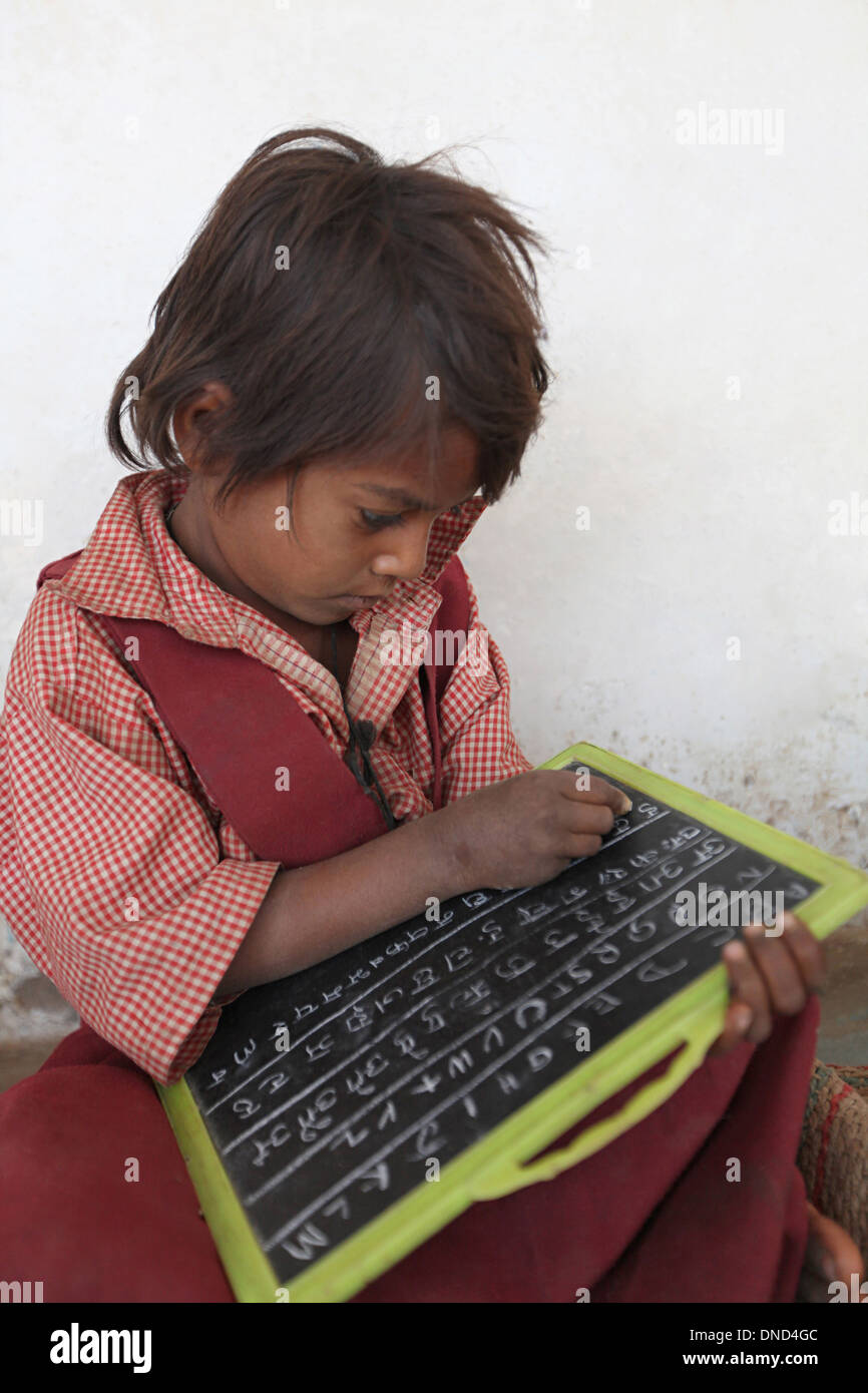 A girl studying at Ashram school writing with chalk on slate, Rangapura, Zabua district, Madhya Pradesh Stock Photo