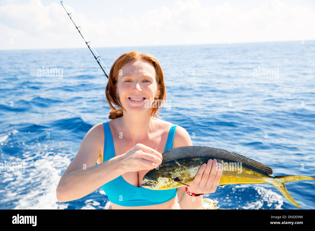 Woman fishing Dorado Mahi-mahi fish happy with trolling catch on boat deck Stock Photo