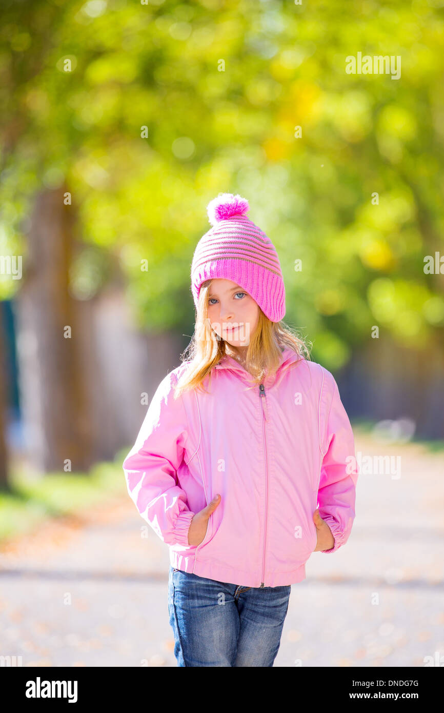 autumn winter kid girl blond with jeans and pink snow cap in trees track Stock Photo