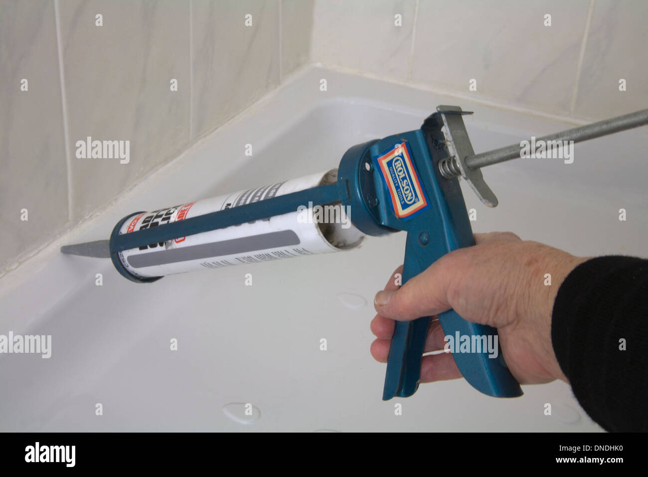 Woman squeezing trigger of gun with silicone filler attached to repair