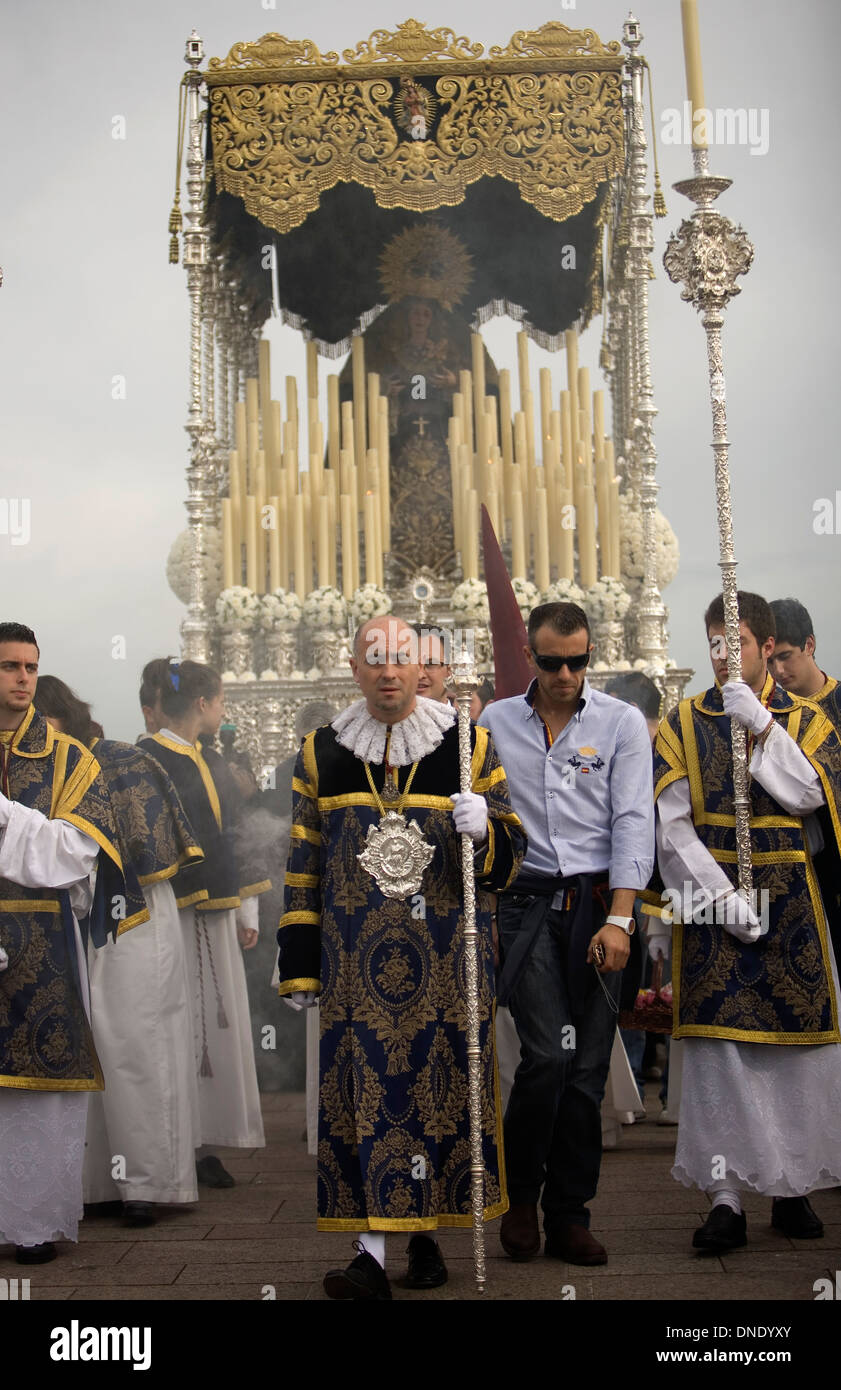 Acolytes walk in front of a throne displaying an image of the Virgin Mary during an Easter Holy Week procession in Cordoba,Spain Stock Photo