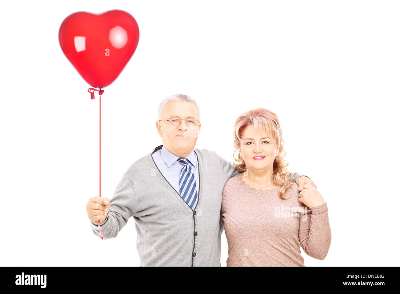 Middle aged couple in hug holding a red heart balloon Stock Photo