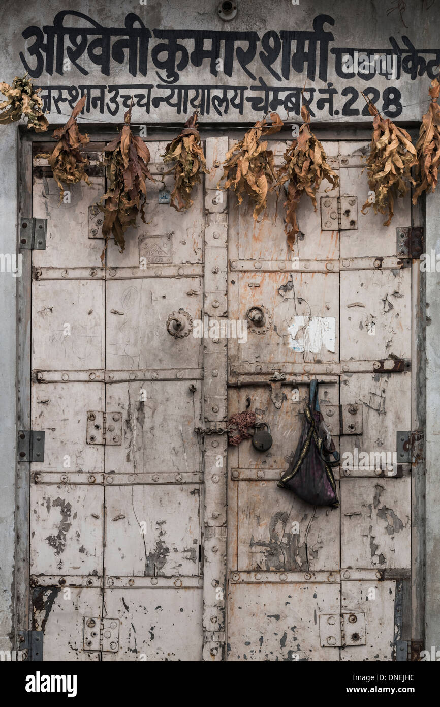 India, Rajasthan, Jaipur, old, textured wooden door with Hindi writing and dried leaves Stock