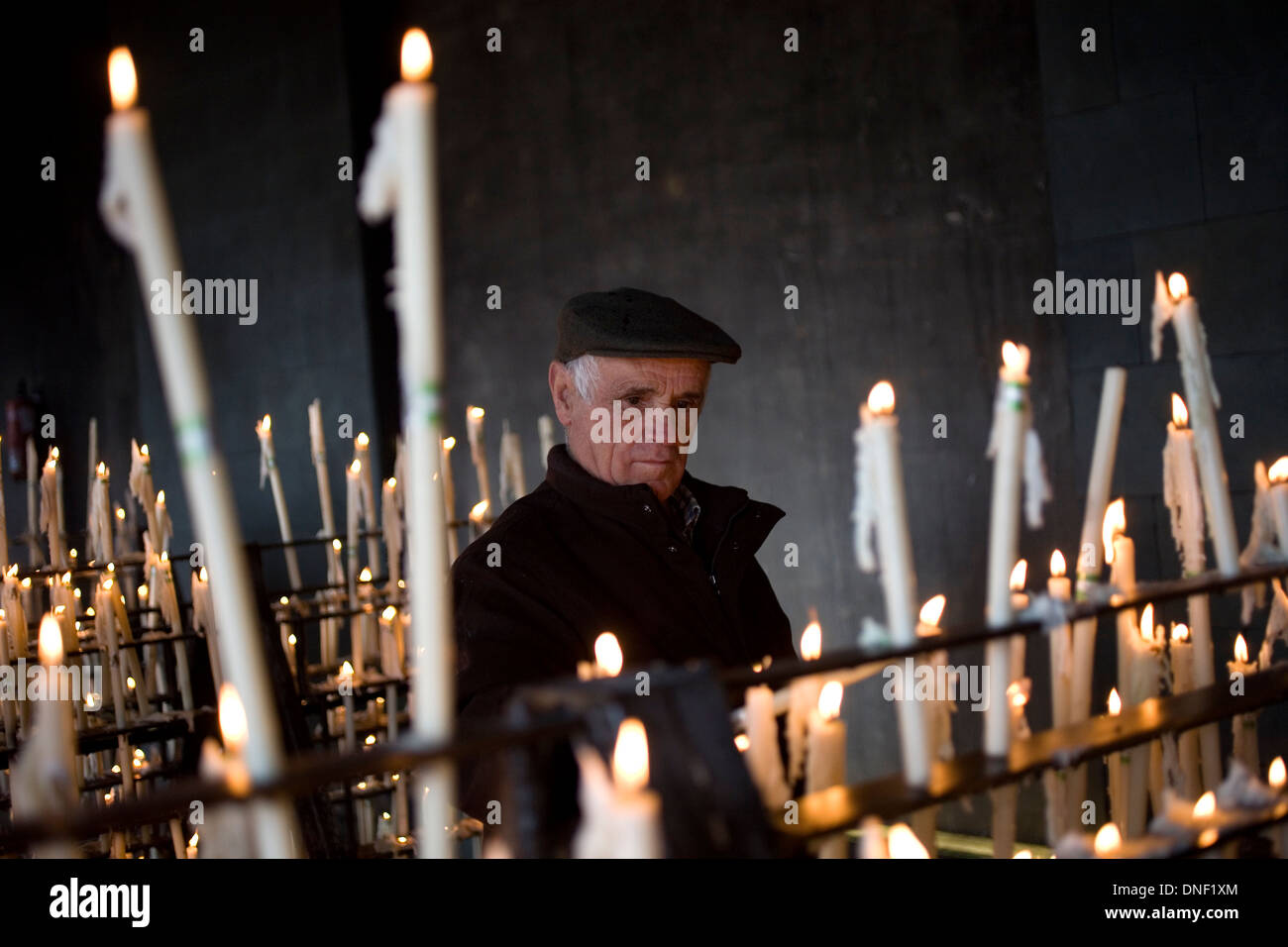 A senior man lights a candle in the votive room of the Sanctuary of Our Lady of Rocio in El Rocio village, Andalusia, Spain Stock Photo
