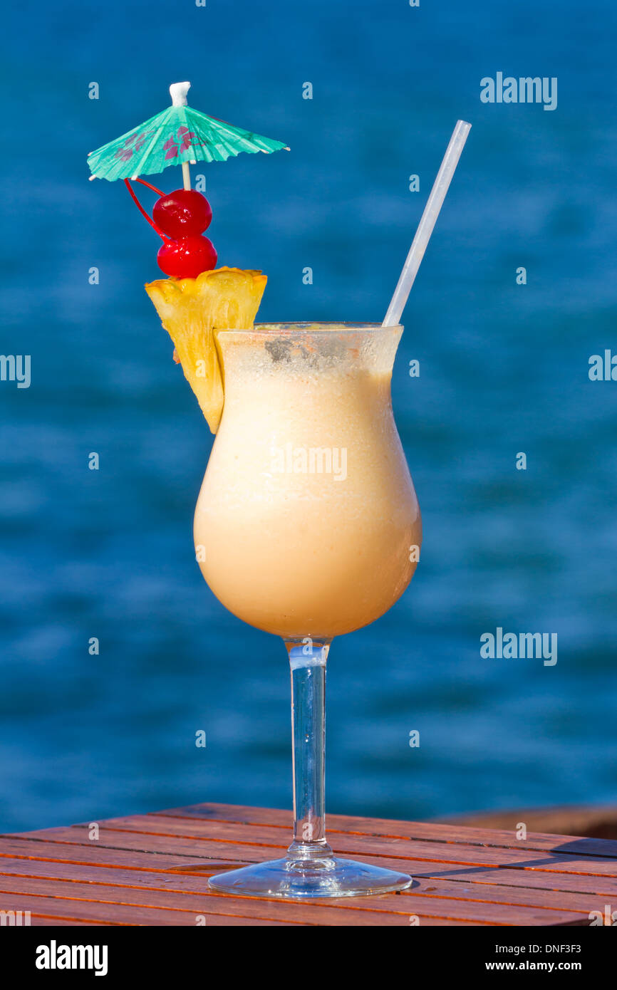 pina colada served on the beach garnished with fresh pineapple and cherries  Stock Photo - Alamy