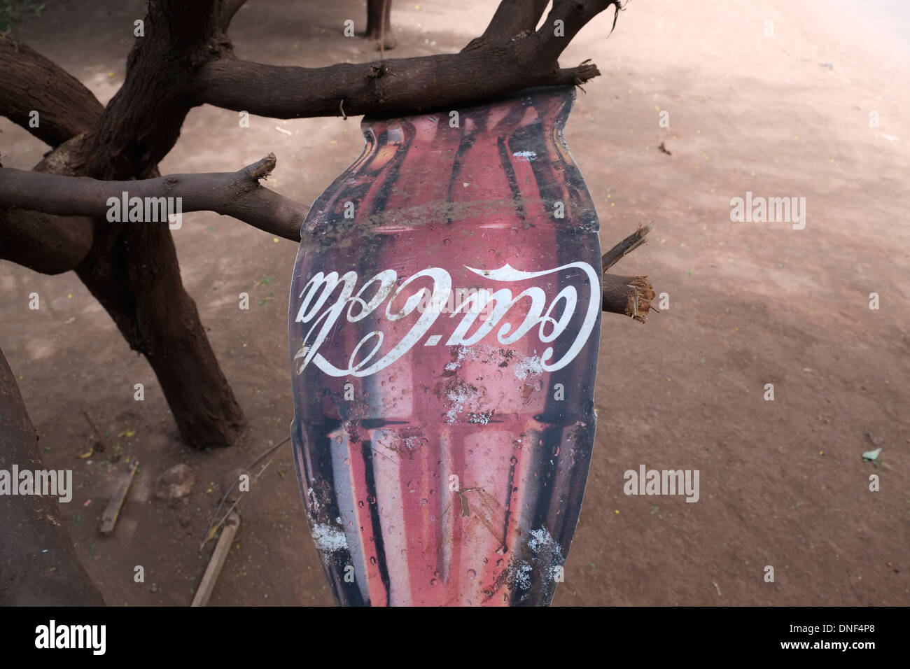 A sign in the shape of a classic Coca Cola bottle in a remote village
