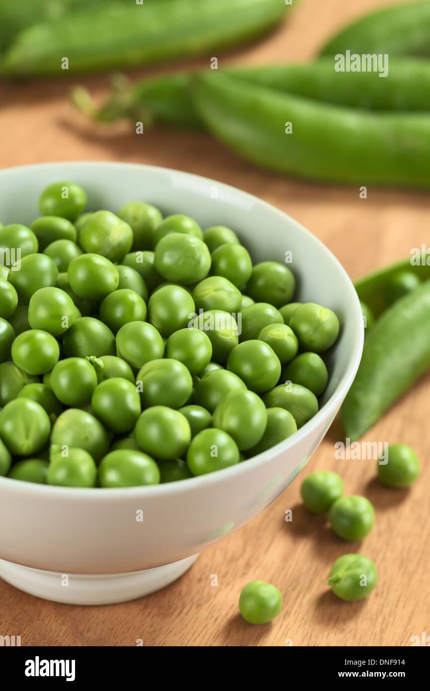 Fresh raw green pea (lat. Pisum Sativum) in white bowl (Selective Focus, Focus on the peas in the middle of the bowl) Stock Photo