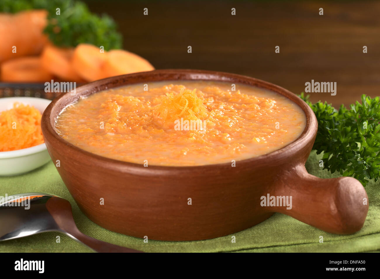 Carrot cream soup garnished with a small pile of grated carrots Stock Photo