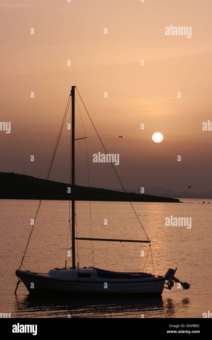 Sunset on the coast with a sailboat Stock Photo