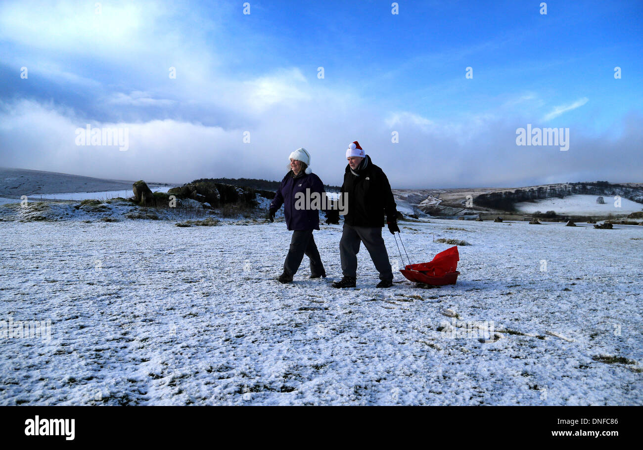 Buxton, Derbyshire, UK. 25th Dec, 2013.  After waking up to a white Christmas, Colin Chandler and Judith Irwin use a sledge to deliver Christmas presents on Christmas Day in Buxton in the Derbyshire Peak District. Credit:  Joanne Roberts/Alamy Live News Stock Photo
