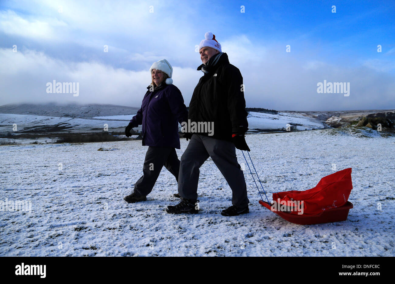 Buxton, Derbyshire, UK. 25th Dec, 2013.  After waking up to a white Christmas, Colin Chandler and Judith Irwin use a sledge to deliver Christmas presents on Christmas Day in Buxton in the Derbyshire Peak District. Credit:  Joanne Roberts/Alamy Live News Stock Photo