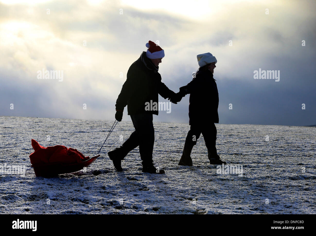 Buxton, Derbyshire, UK. 25th Dec, 2013.  After waking up to a white Christmas, Colin Chandler and Judith Irwin use a sledge to deliver Christmas presents on Christmas Day in Buxton in the Derbyshire Peak District. Credit:  Joanne Roberts/Alamy Live News Stock Photo