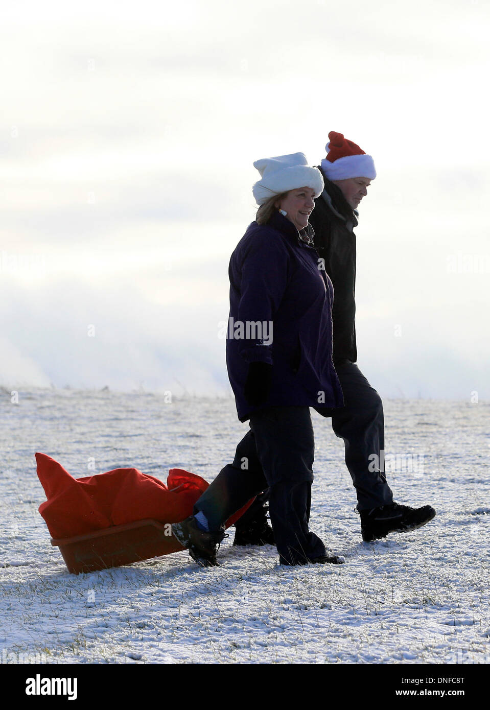 Buxton, Derbyshire, UK. 25th Dec, 2013.  After waking up to a white Christmas, Colin Chandler and Judith Irwin use a sledge to deliver Christmas presents on Christmas Day in Buxton in the Derbyshire Peak District. Credit:  Joanne Roberts/Alamy Live News Stock Photo