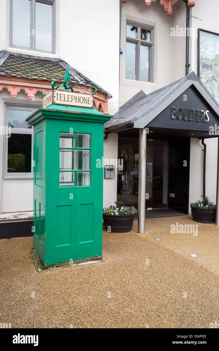 Old green vintage telephone box by the entrance to Boulters Restaurant and Bar Boulters Lock Island Maidenhead Berkshire UK Stock Photo