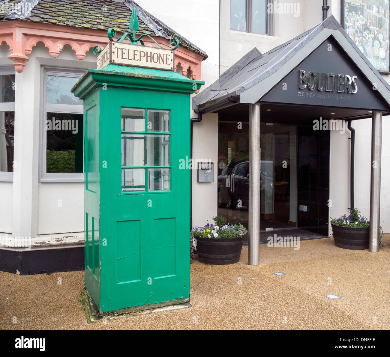 Old green vintage telephone box by the entrance to Boulters Restaurant and Bar Boulters Lock Island Maidenhead Berkshire UK Stock Photo
