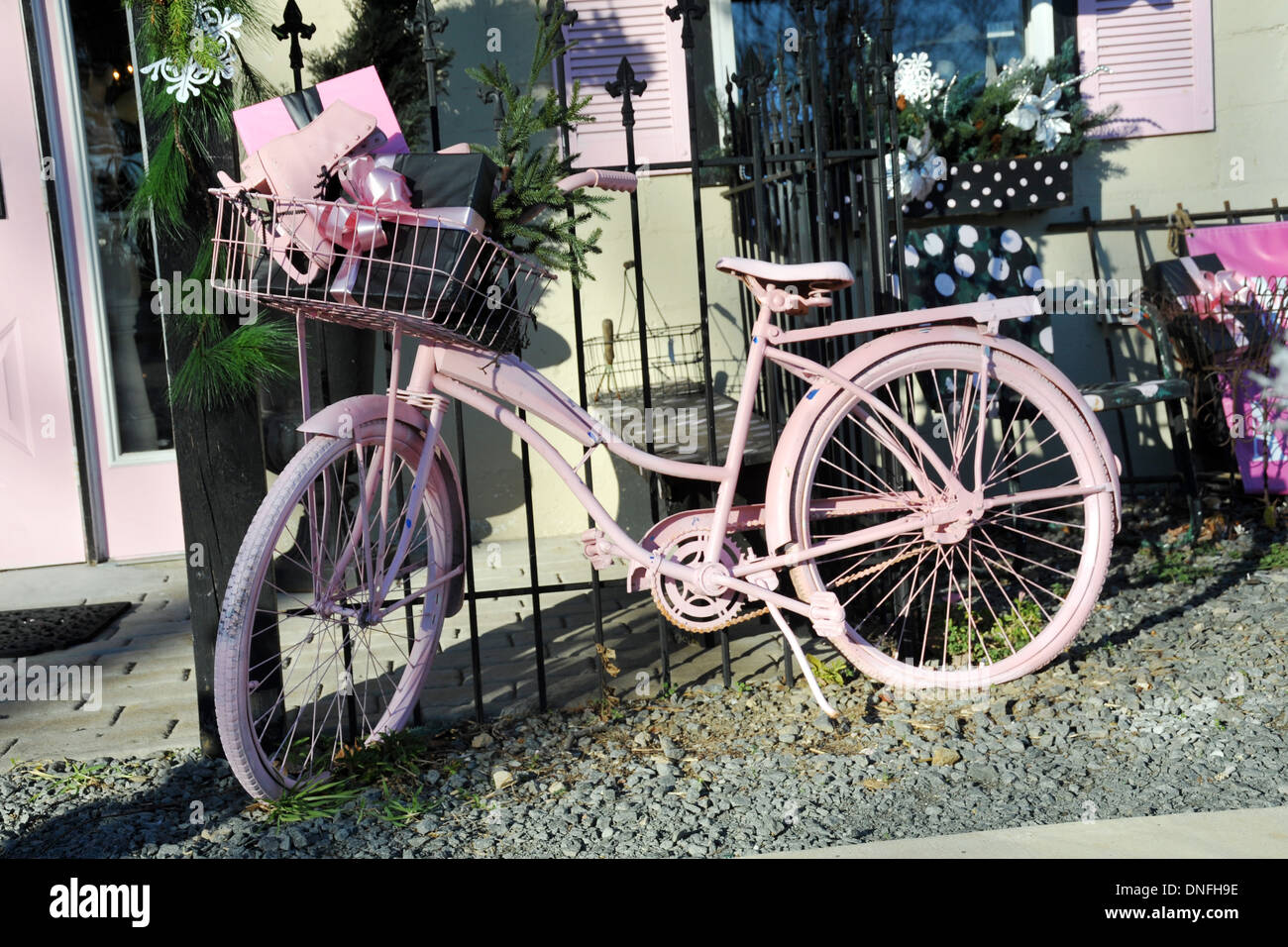 Gift in girls pink bicycle basket parked against black iron fence, Stock Photo