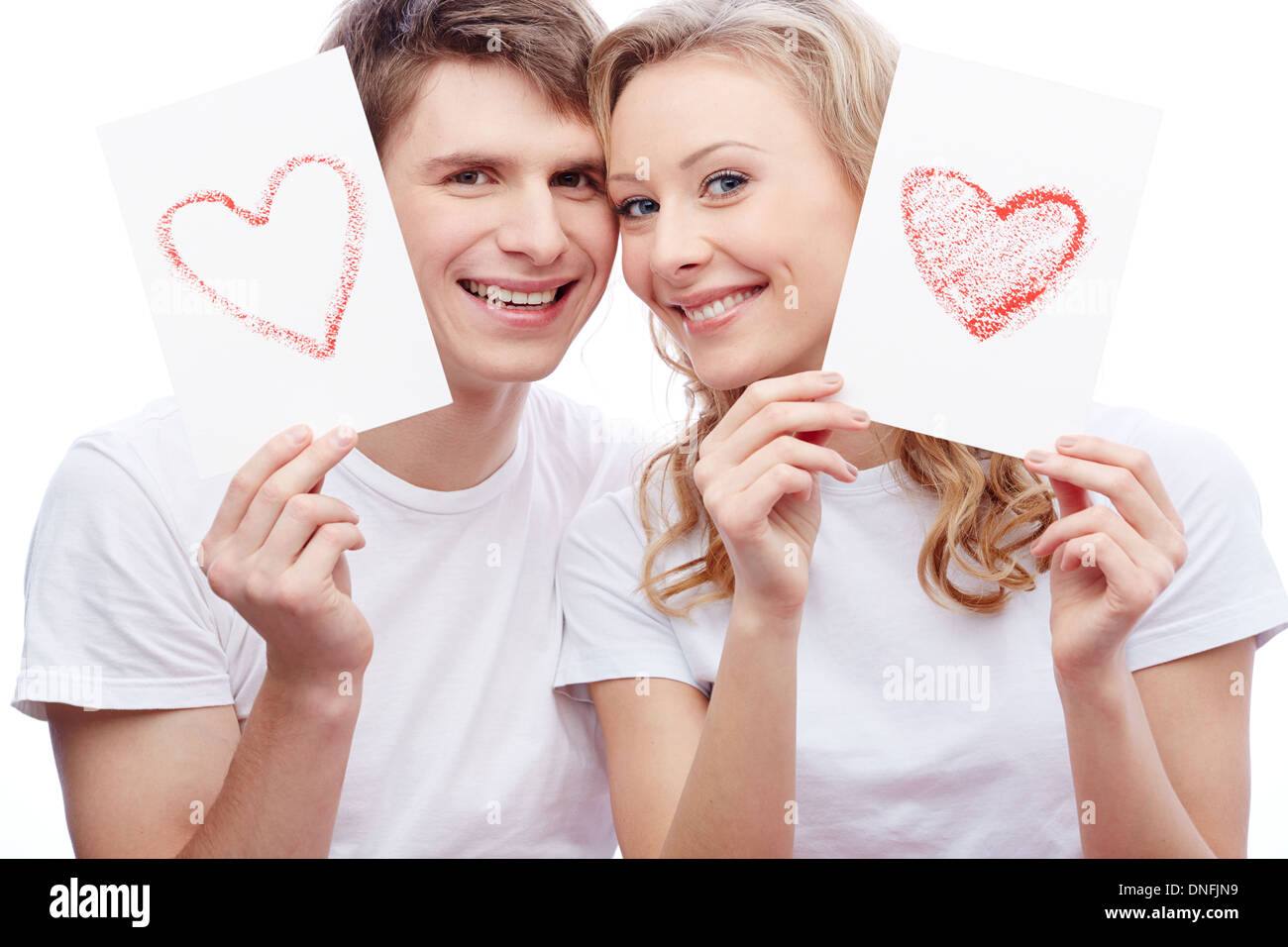 Portrait of young amorous couple looking at camera while holding papers ...
