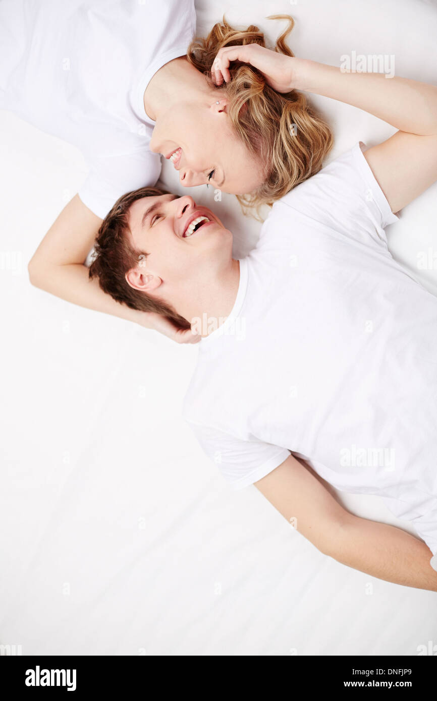 Two happy young dates lying in bed and laughing Stock Photo