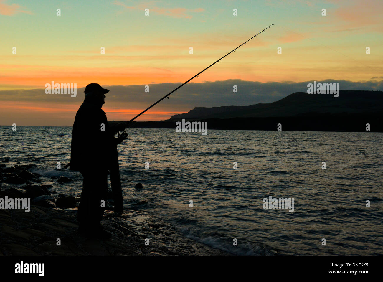 Angler fishing in the last light of evening at Kimmeridge Bay, Dorset Stock Photo