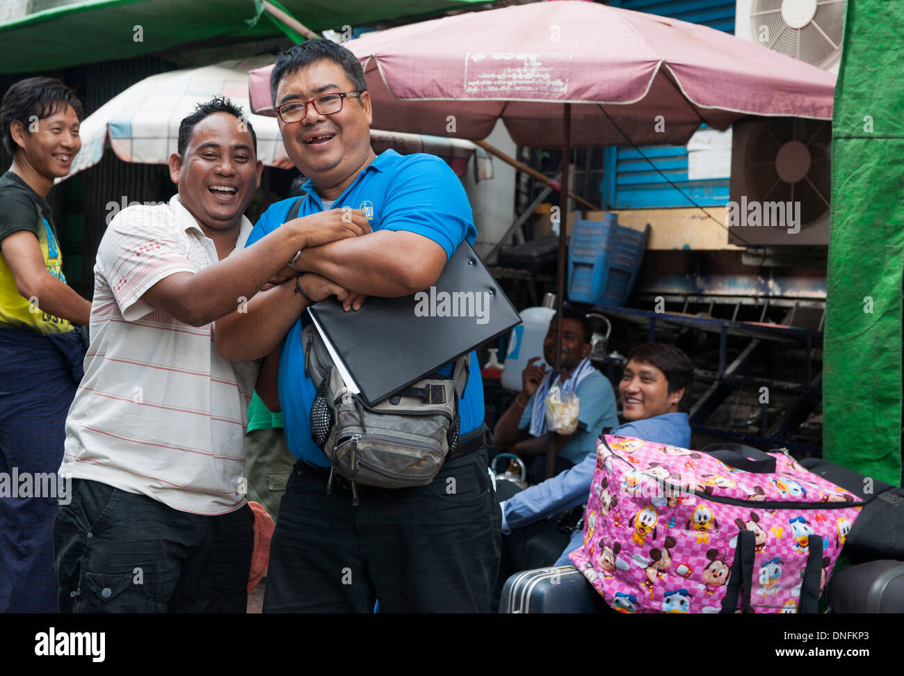 Two Burmese men sharing a joke and smiling at the camera in Yangon street, Myanmar. Stock Photo