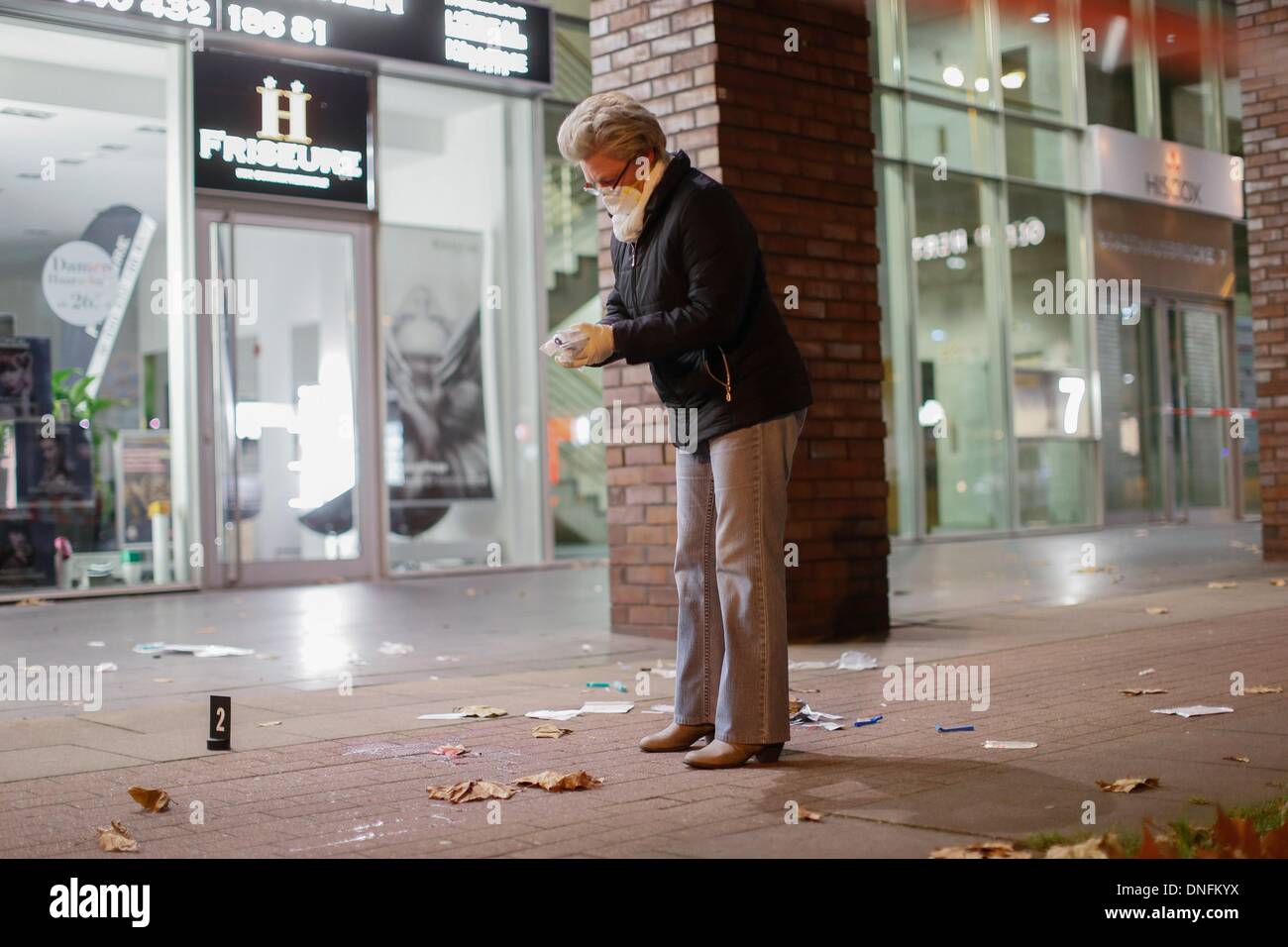 A female forensic expert of the Hamburg Police inspects a crime scene in Hamburg, Germany, 25 December 2013. A woman stabbed and fatally injured a man on the street during an escalated dispute. Photo: Paul Weidenbaum/dpa Stock Photo