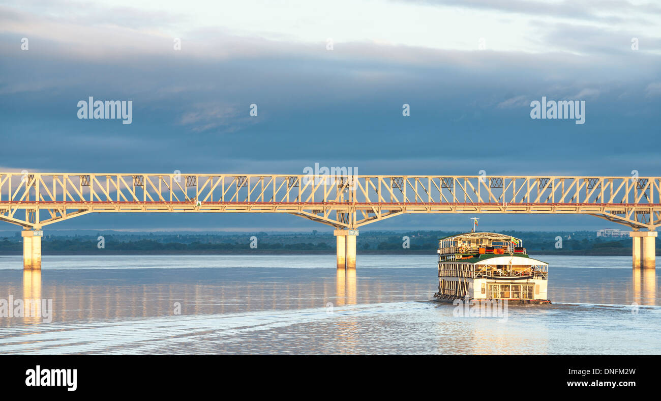 Tourist boat approaches the Pakokku Bridge across the Irrawaddy River in Myanmar. Myanmar travel and people images. Stock Photo