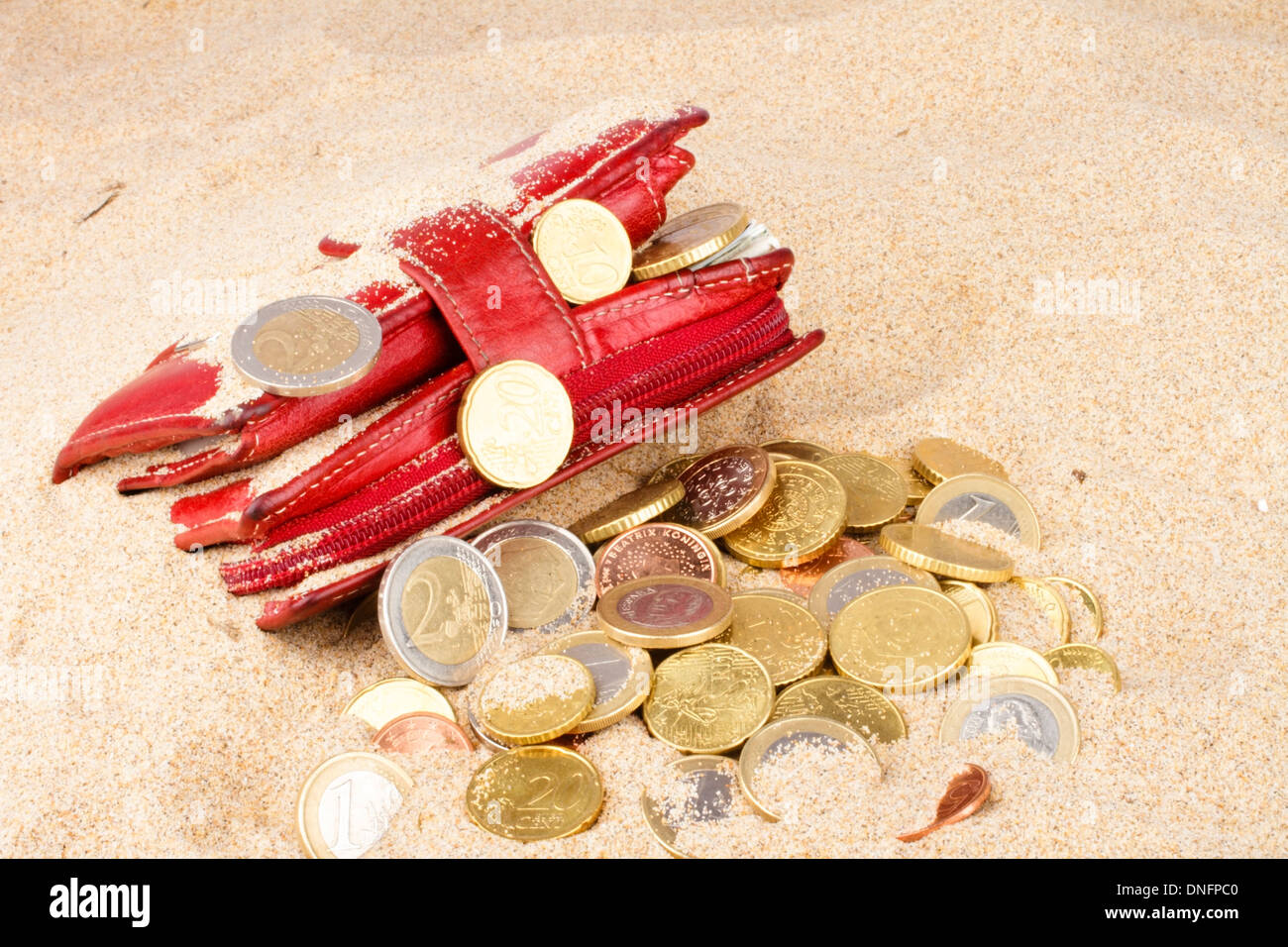 Red wallet with euro coins in the sand Stock Photo