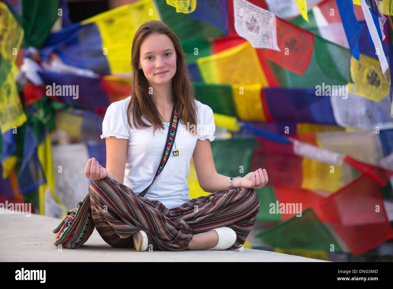 Girl sitting in the Lotus position on Buddhist stupa, prayer flags