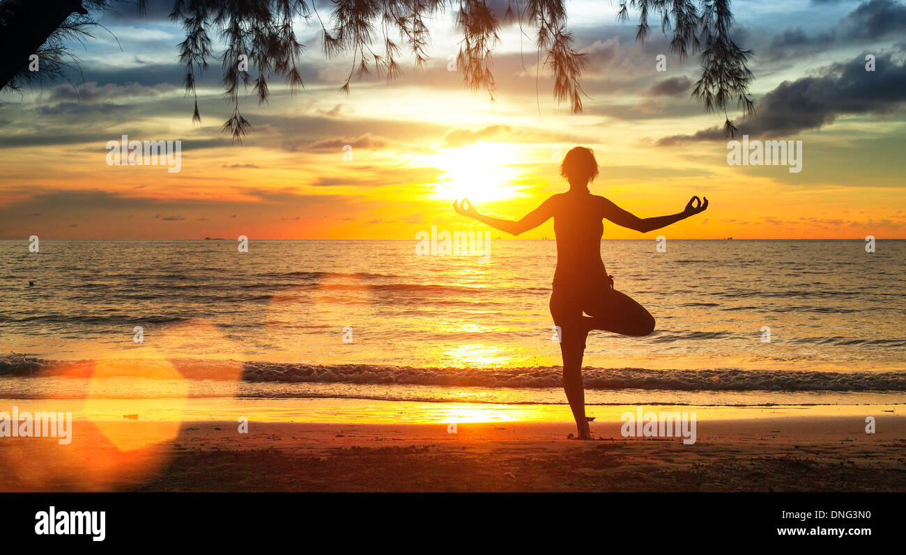 Young yoga woman silhouette. Exercises on the beach during a beautiful ...