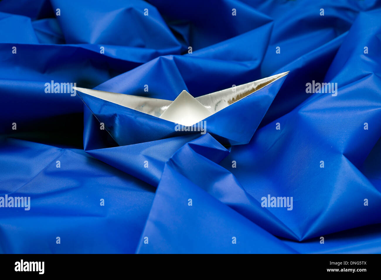 Paper boat on blue fabric Stock Photo