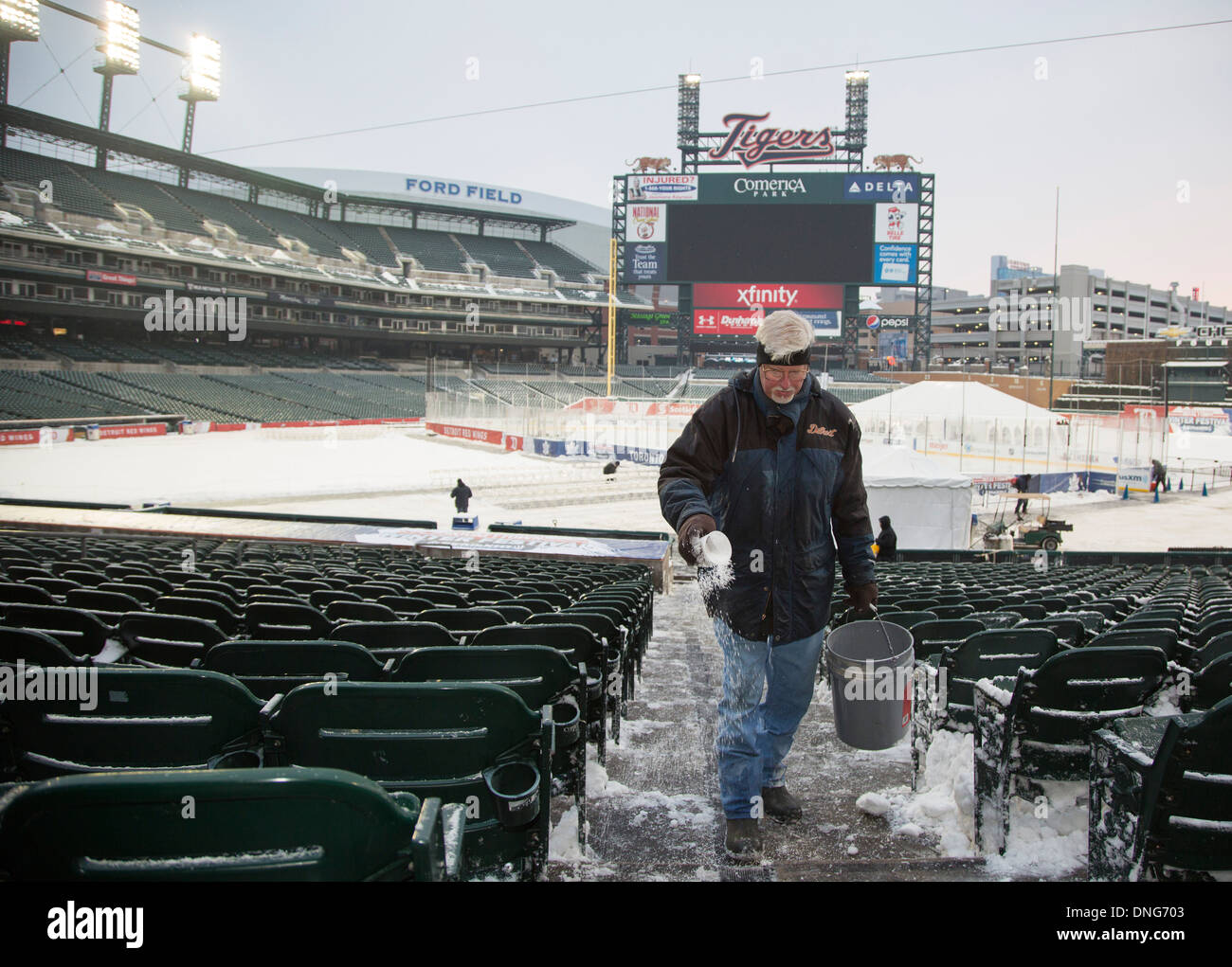 A worker sprinkles de-icer on steps at Comerica Park before an ice hockey game during the Hockeytown Winter Festival. Stock Photo